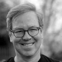 Head shot of Jose. The photo is in black and white. Jose wears glasses