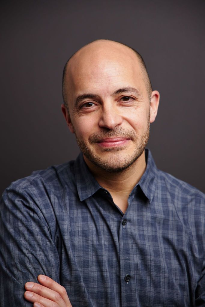Head shot of Michel Anteby, wearing a blue shirt. He stands in front of a black background