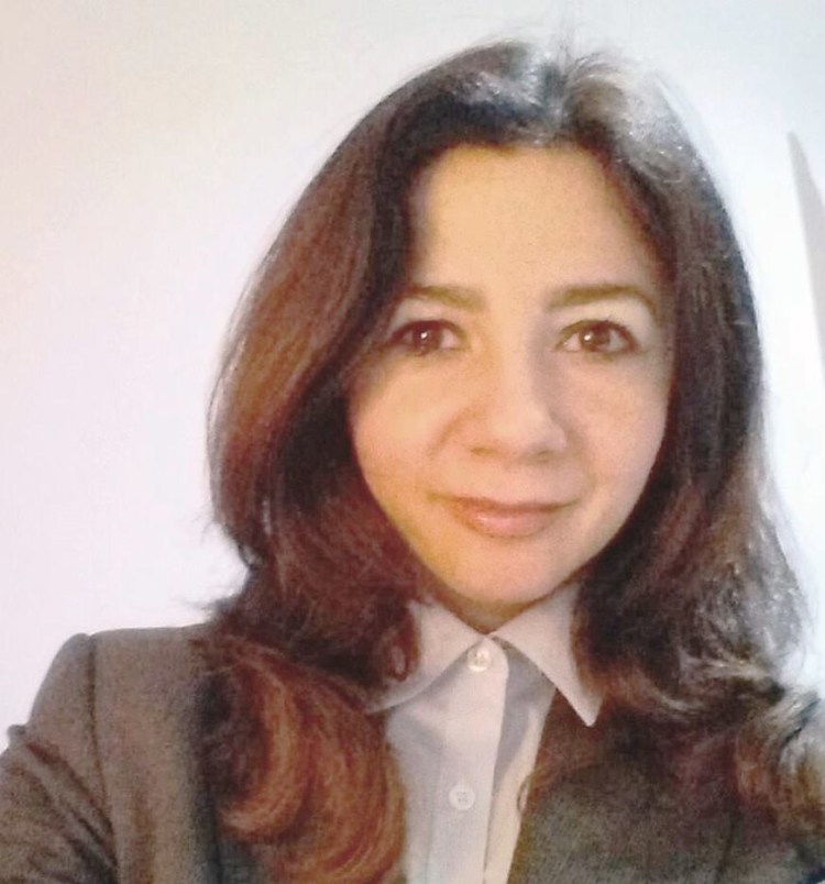 Headshot of Paula who has shoulder long brown hair and wears a grey jacket