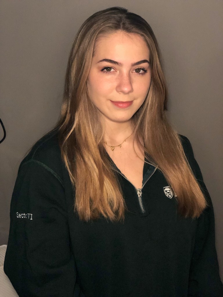 head shot of Kerra who has long dark blonde hair and wars a black university jumper