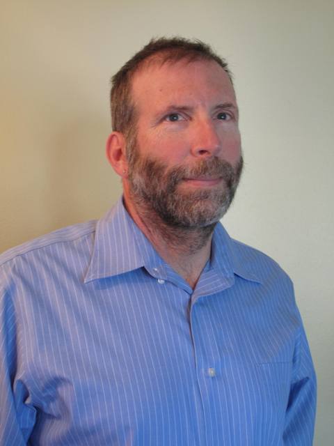 head shot of Dan Lococo a man with brown short hair and a beard wearing a blue striped shirt