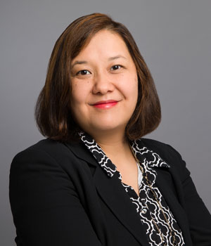 Photo of Keimei Sugiyama who has shoulder length dark hair. She wars a black jacket with a patterned black and white top underneath