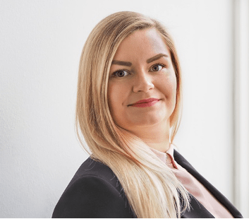 Headshot of Maleen Halter who stands sideways facing the camera. Maleen has long blonde hair and wears a dark jacket over a light top.