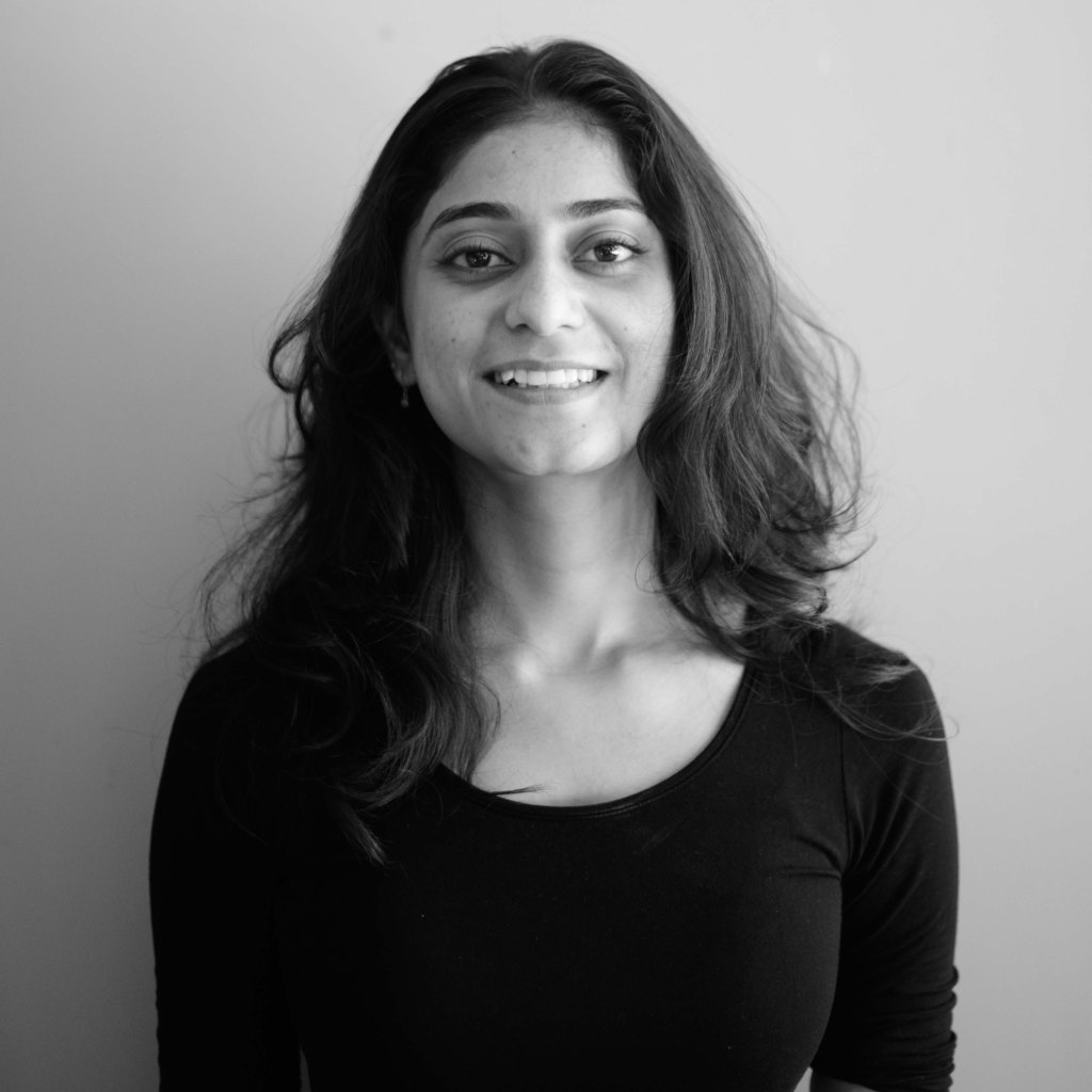 black and white head shot of Aishwarya Bali , an Indian woman smiling broadly at the camera.