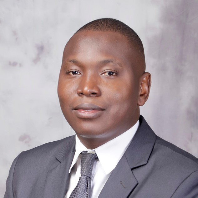 head shot of Israel Adekunle Balogun, a black man with short hair wearing a suit and tie, both are grey