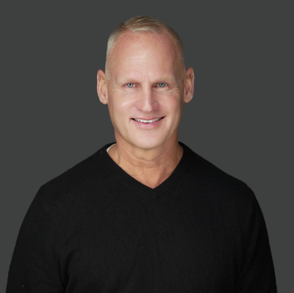 headshot of Hans Hansen, a middle-aged white man with short hair wearing a black top