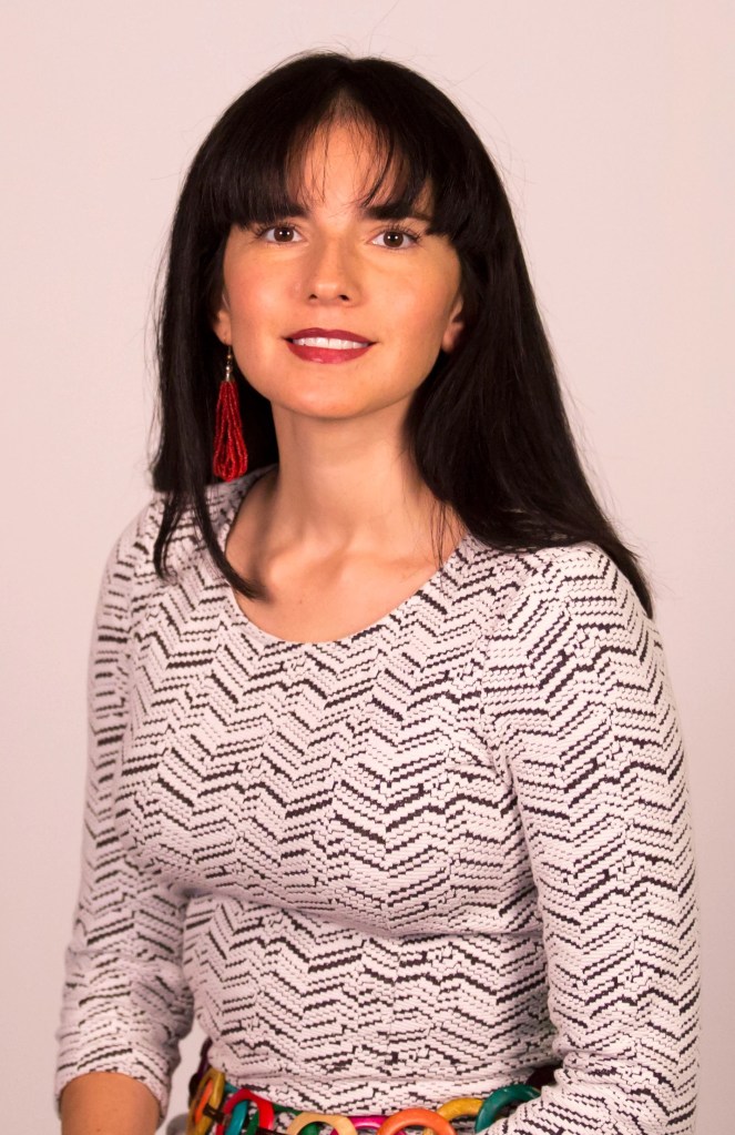 headshot of Mar Peretz who has long black hair and wears long red hanging earrings