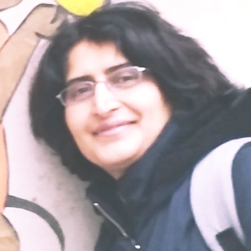 headshot of Jennifer Thaler sitting sideways with her knees up resting her elbow on the knee and touching her head. Her hair is black