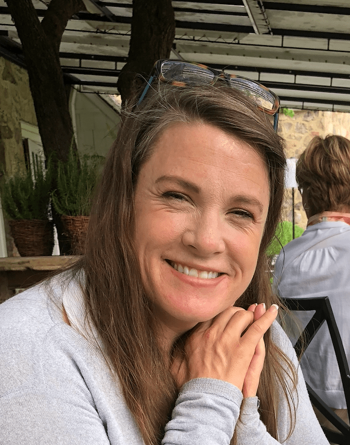 headshot of Frances Strezer who has dark blonde hair. Frances sits in a cafe and we see other people's backs in the background