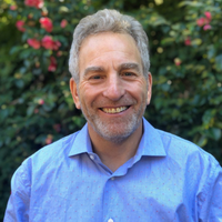 headshot of Steve Zuckerman, a white man with short grey hair wearing a blue shirt