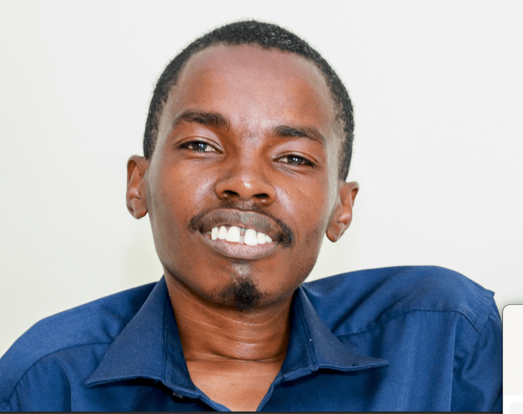 Photo of a black man smiling broadly and wearing a blue shirt